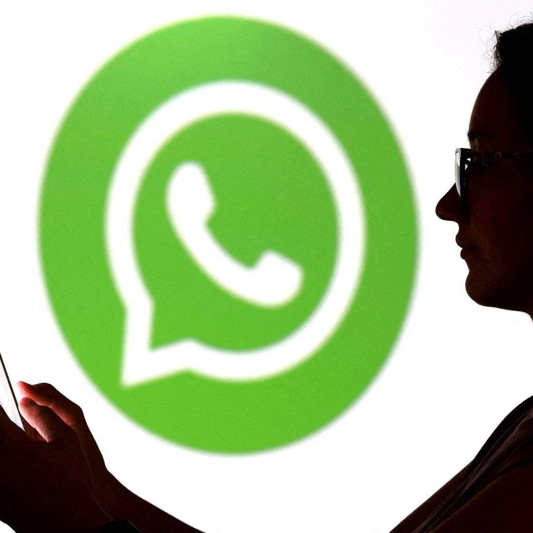 Un adolescente posa para una foto sosteniendo un teléfono inteligente frente al logotipo de WhatsApp. Foto: Reuters
